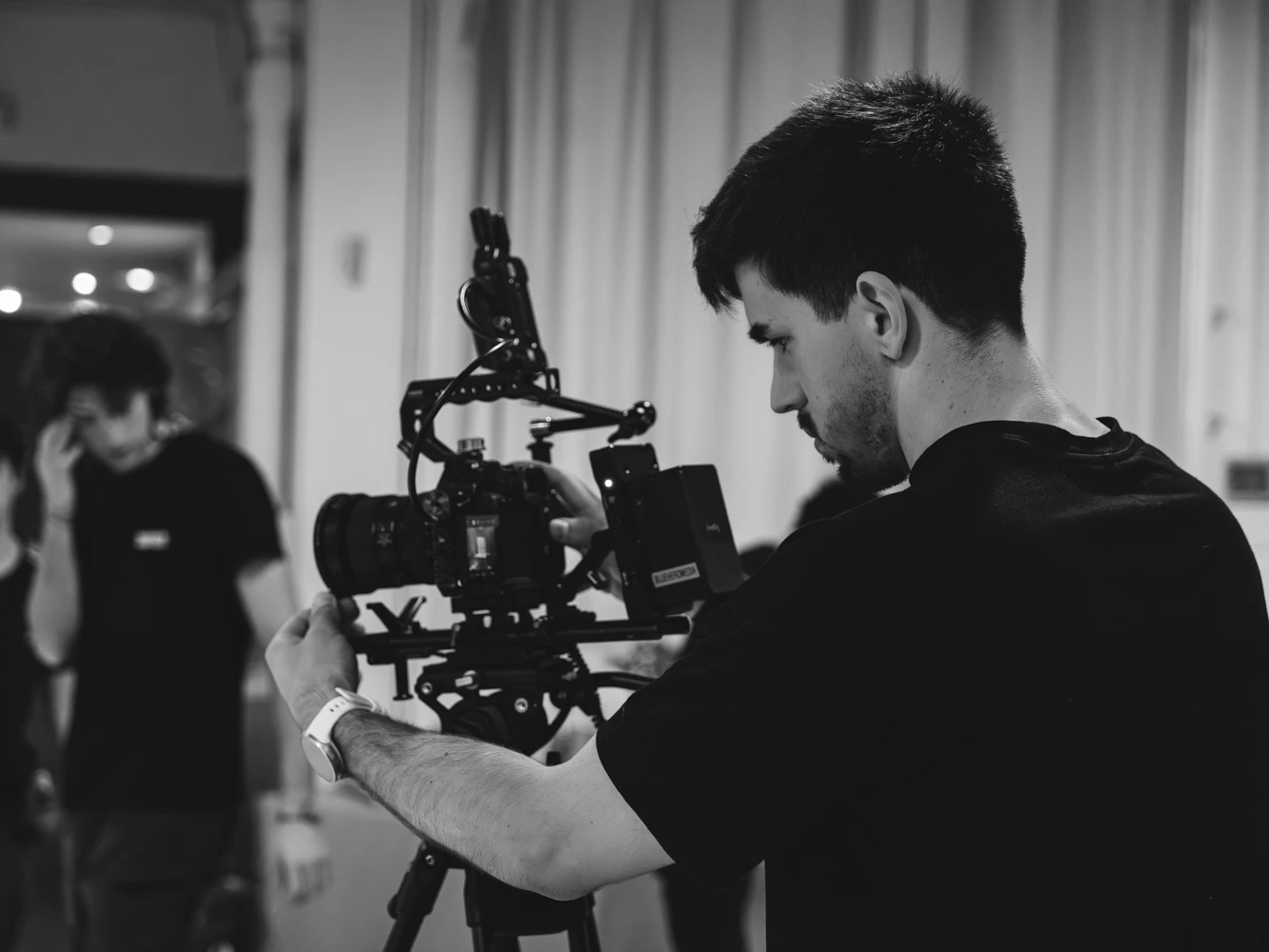 Black-and-white shot of a camera operator adjusting his rig on a Tasty Studio set