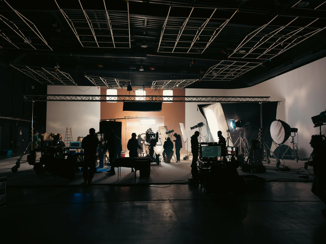 Wide view of a large film studio with the Glassy Films crew working in silhouette