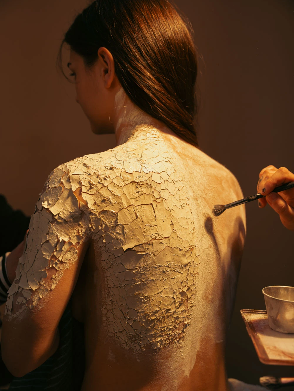 Cracked clay texture being brushed onto a model's back for a Tasty Studio beauty shot